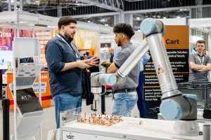Advanced Engineering 2026 Innovation Gallery preview: visitors talk beside a collaborative robot arm demo on an exhibitor stand