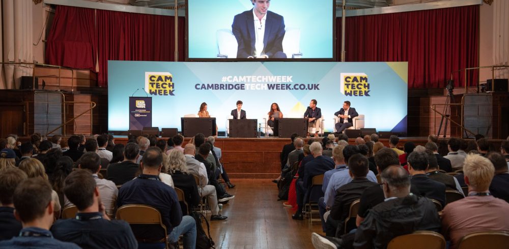 Panel discussion on stage in front of a packed audience at Cambridge Tech Week 2026