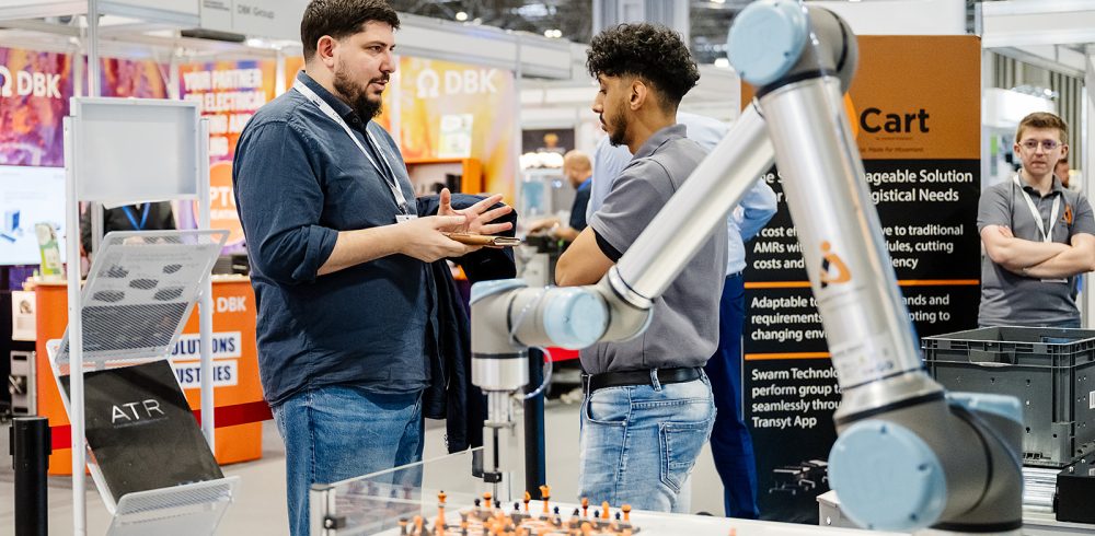 Advanced Engineering 2026 Innovation Gallery preview: visitors talk beside a collaborative robot arm demo on an exhibitor stand