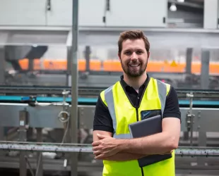 Portrait of smiling factory worker standing with a digital tablet in the factory