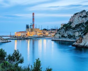 Mediterranean coast with power plant and its coal pier in the town.