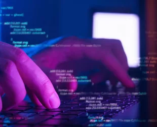programmer or hacker coding on laptop in dark room