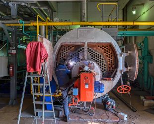 Worker repairing the boiler with the aid of welding